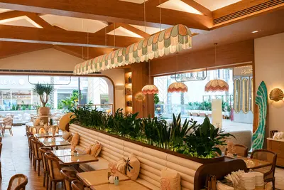 A timber coffered ceiling above banquette seating and planting at Aurora, Kuwait City