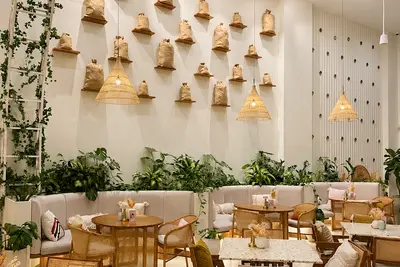 A wall of woven pendant shades above cane chairs and marble tables at Al Liwan