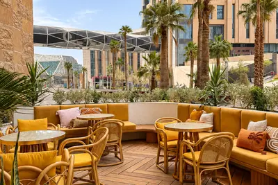 Yellow banquettes and rattan chairs on the terrace at KAFD, the district towers behind