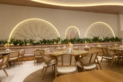 Timber chairs and round tables below arched, planted alcoves at Palm Jumeirah Mall