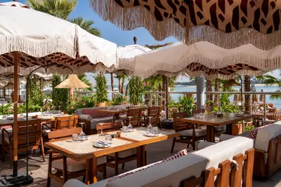 Fringed parasols over timber dining tables on the beach terrace at Canary Beach