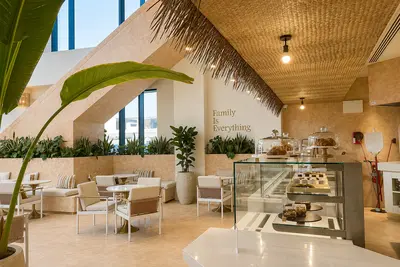 A woven cane ceiling above pale timber chairs and the counter at Olas