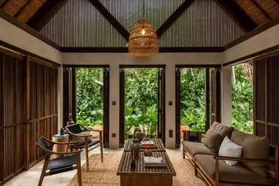 Armchairs and a low table in a timber pavilion open to the garden at Tampah Hills