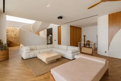 A pale sectional sofa in the double height living space beneath Villa Babylon's spiral staircase