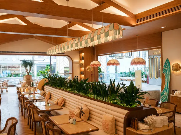Un techo artesonado de madera sobre bancos corridos y plantas en Aurora, Ciudad de Kuwait