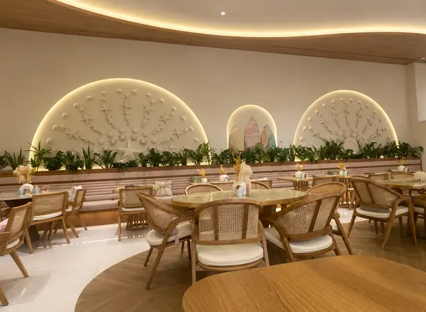 Timber chairs and round tables below arched, planted alcoves at Palm Jumeirah Mall