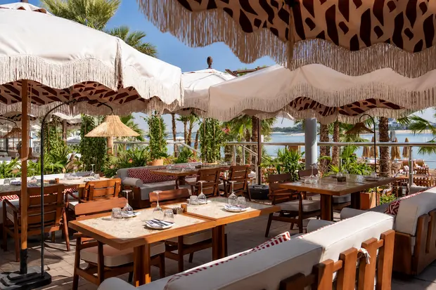 Fringed parasols over timber dining tables on the beach terrace at Canary Beach