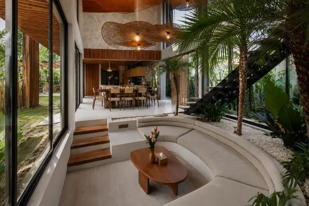 The sunken lounge at Villa Livare, a curved sofa and oval timber table below the dining room